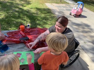 girl in wheelchair helping boy with craft